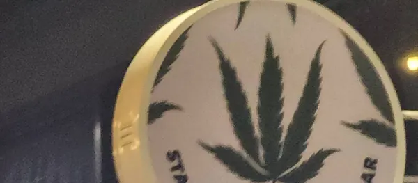 Stash BKK Ari — round cannabis-leaf sign in the lounge