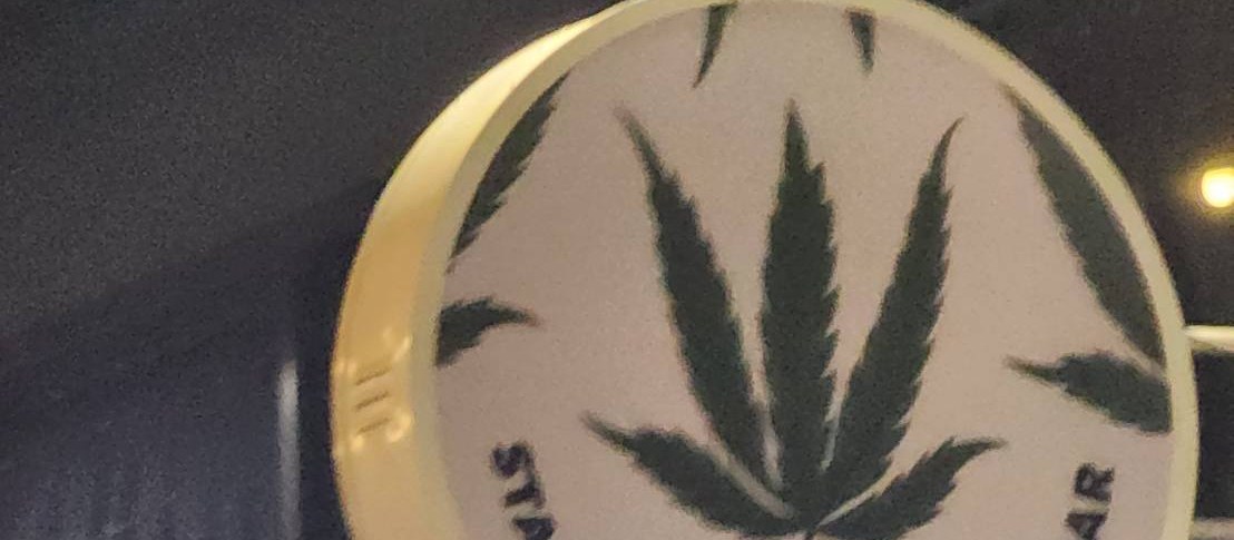 Stash BKK Ari — round cannabis-leaf sign in the lounge